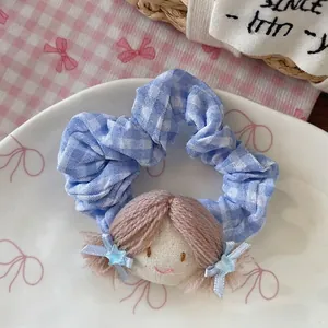 Détail du chouchou à carreaux bleus avec tête de poupée et étoiles dans un plat blanc