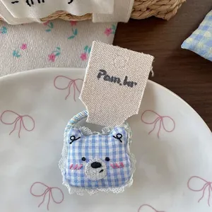 Vue détaillée de l'accessoire cheveux ours à carreaux bleus avec dentelle et broderie