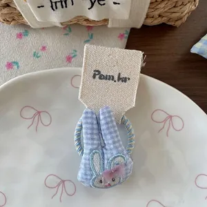 Vue détaillée du chouchou oreille de lapin à carreaux bleus avec nœud en maille rose