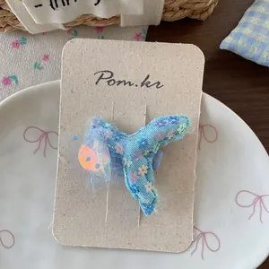 Détail d'une pince à cheveux en tulle bleu avec broderie florale et sequins sur une assiette
