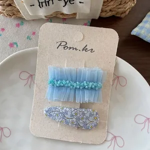 Détail de la pince à cheveux à fleurs bleues et nœud en résille sur une assiette