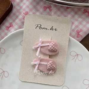 Détail de barrettes en tissu rose avec cœur à carreaux et nœuds sur carte de support