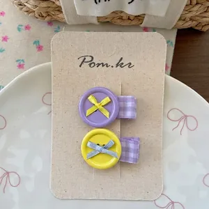 Detail of sweet button hair clips with ribbon bows on a textured display card