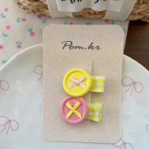 Detail of sweet button hair clips with ribbons on display card and ceramic plate