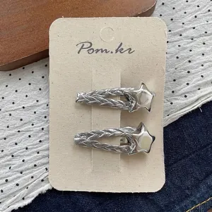 Detail of two silver star-shaped woven metal hairpins on a textured display card