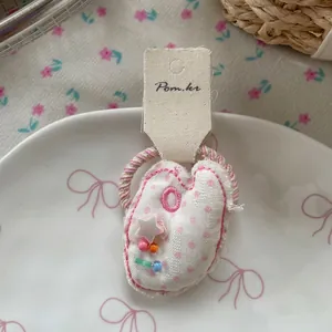 Vue détaillée du chouchou en tissu en forme de cœur à pois roses avec perles mignonnes