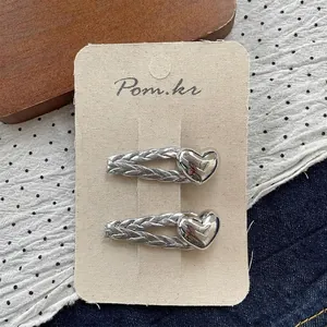 Macro shot of silver heart hair clips with woven metal texture on a card board