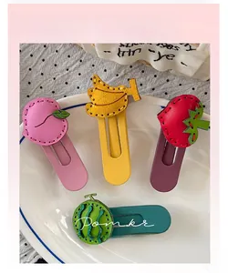 Detail view of handmade faux leather fruit hair clips with visible stitching on white plate