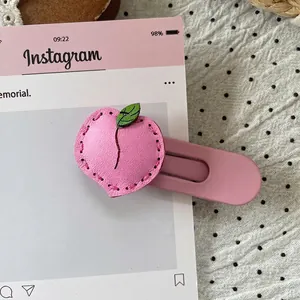 Close-up of pink leather peach hair clip with exquisite stitching and green leaf detail