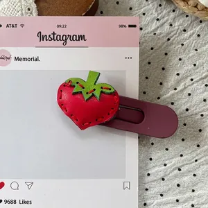 Close-up of strawberry faux leather hair clip with red hand-stitched detailing