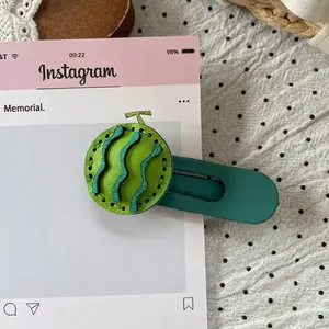 Detail of green melon pattern leather hair clip with wavy stitching on a gift card