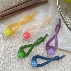 Five minimalist colorful resin banana hair clips for buns on a styled background