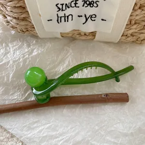 Detailed close-up of a translucent emerald green banana hair clip on a natural wood branch