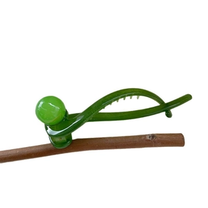 Minimalist green resin banana hair clip with ball detail on a natural branch