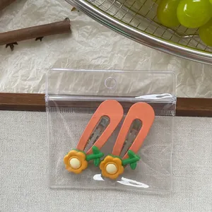 Detail von zwei orangefarbenen Blumen-Haarspangen mit Harz-Anhängern in Verpackung