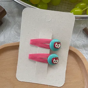 Pink fabric clips with light blue dots and red apple detail on a display card