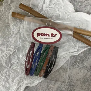 Close-up of five colorful teardrop hair clips in premium transparent packaging