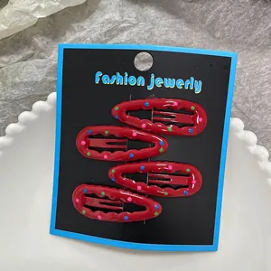 Close-up of four red metal hair clips with colorful polka dots on a display card