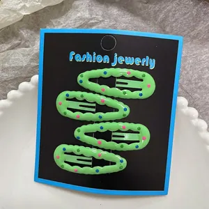 Close-up of four green polka dot snap hair clips on a jewelry card display