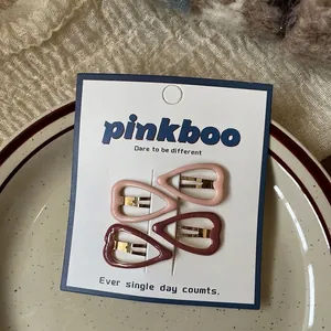 Close-up of four heart-shaped hair clips in pink and deep red on a white card display