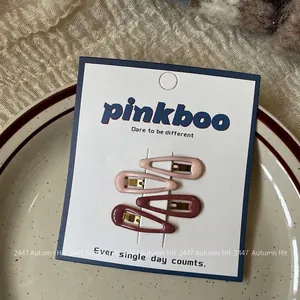 Detailed view of four teardrop-shaped pink and red hair clips on a gift card display