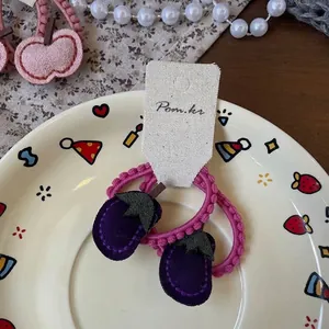 Détail d'un chouchou en tissu aubergine violette et élastique à perles roses pour enfants