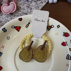 Détail d'élastiques en tissu jaune avec breloque poire verte sur assiette