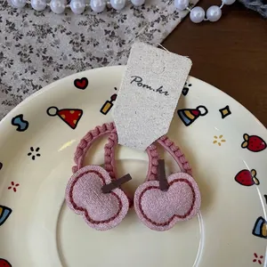Détail de chouchous cerise en tissu rose poudré présentés sur une assiette décorative