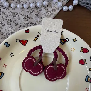 Détail des élastiques à cheveux en tissu cerise faits main avec couture blanche précise