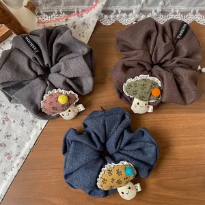 Trois chouchous motif champignon en gris, marron et bleu marine avec détails floraux