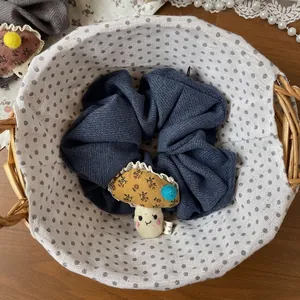 Gros plan d'un chouchou bleu marine avec un pendentif champignon dans un panier