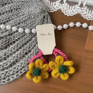 Détail de chouchous fleurs jaunes crochetés main sur une carte de présentation crème