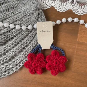 Gros plan de barrettes à fleurs crochetées à la main avec pétales rouges et cœur bleu