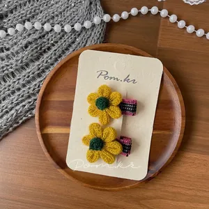 Détail de barrettes à fleurs en tricot faites main avec des rubans à carreaux
