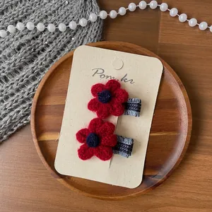 Lot de deux barrettes à fleurs rouges tricotées à la main sur un plateau en bois