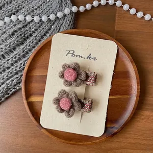 Détail de pinces à cheveux fleurs tricotées à la main avec pétales marrons et tissu