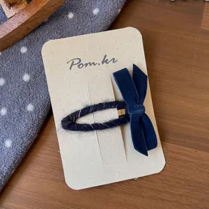 Nahaufnahme einer Samt-Schleifen-Haarklammer mit marineblauem Strick auf Vintage-Holz