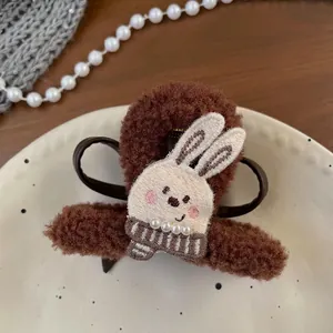 Detail of plush brown hair claw clip featuring cute rabbit embroidery and faux pearls