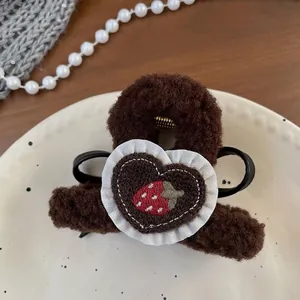 Detailed macro view of brown plush hair claw clip with heart strawberry embroidery
