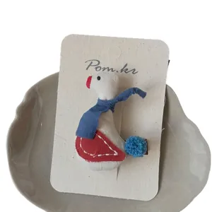 Handgefertigte Stoff-Enten-Haarklammer mit weißem Pompon und blauem Strickschal-Detail