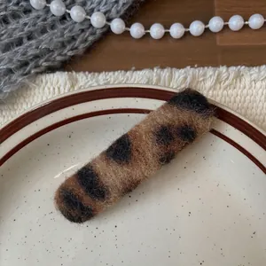 Detail of leopard print plush hair clip with fuzzy texture on a decorative white dish