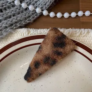 Detailed view of a leopard print triangle hair clip with soft plush fur texture on a plate
