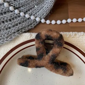 Close-up of leopard print plush hair claw clip on a ceramic tray with warm textures
