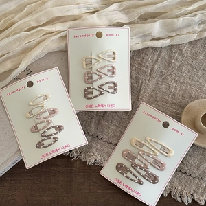 Detail of polka dot hair clips in gradient brown and beige on a display card