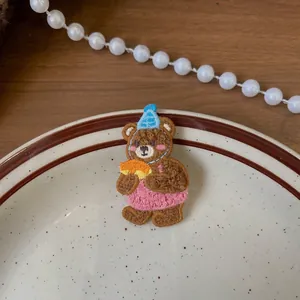 Dettaglio del fermaglio per capelli a forma di orsetto ricamato con cappello da festa