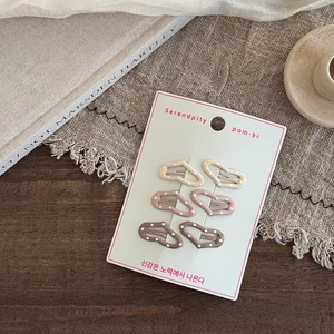 Set of six heart-shaped polka dot hair clips in earthy tones on a display card