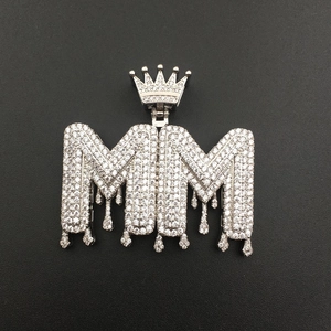 Macro detail of silver hip hop MM letter pendant with crown and pavé cubic zirconia