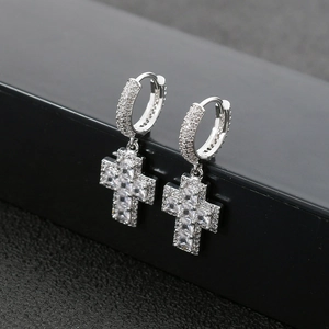 Détail macro de boucles d'oreilles croix hip-hop argentées avec zircons carrés micro-pavés