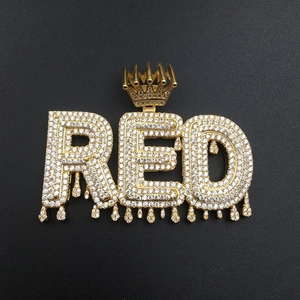 Detailed close-up of golden RED hip-hop pendant with crown bail and iced-out zircons