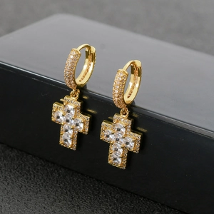 Détail macro de boucles d'oreilles croix dorées avec zircons cubiques micro-pavés